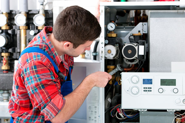 Heating technician repairing boiler controls in Olivehurst