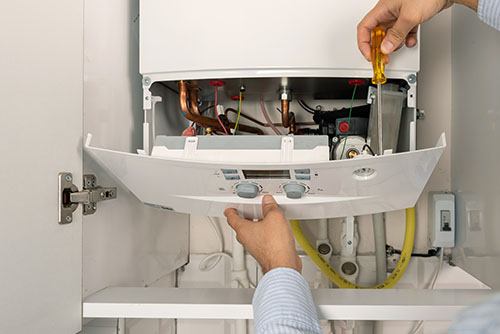 Heating technician repairing a residential boiler in Olivehurst