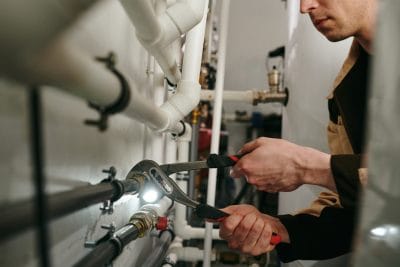 Technician inspecting commercial plumbing pipes in Olivehurst