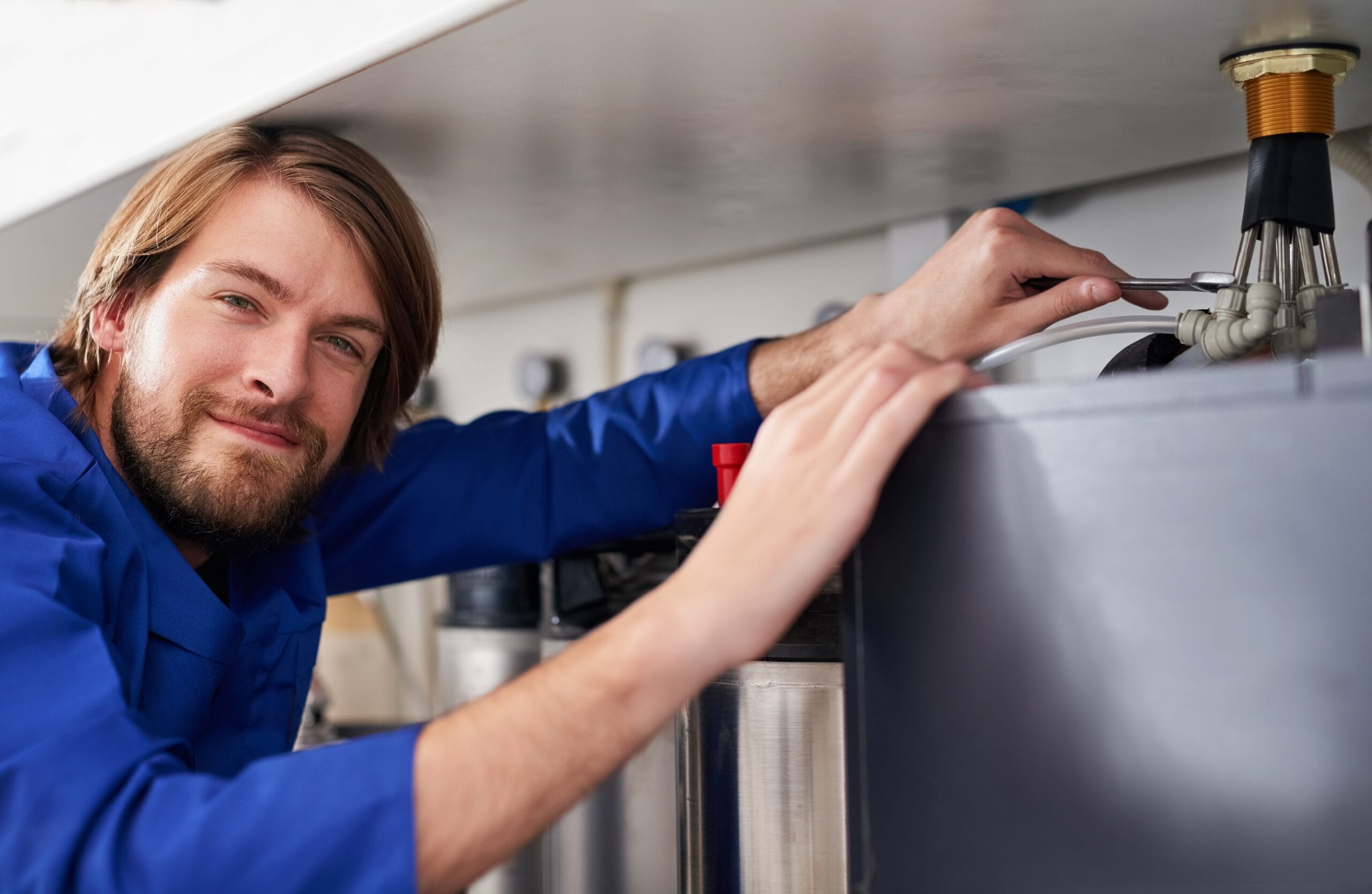 Technician servicing a residential water heater tank in Olivehurst